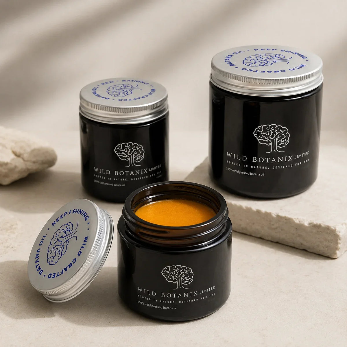 Wild Botanix Cold-Pressed Batana Oil open jar lifestyle image showing the natural orange-gold oil texture